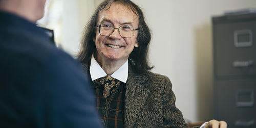 A man talking to another man and smiling.